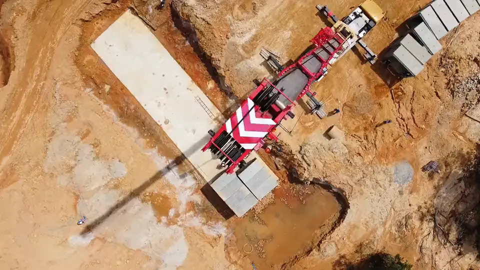 Vista aérea de guindaste içando peças pré-moldadas de concreto em canteiro de obra