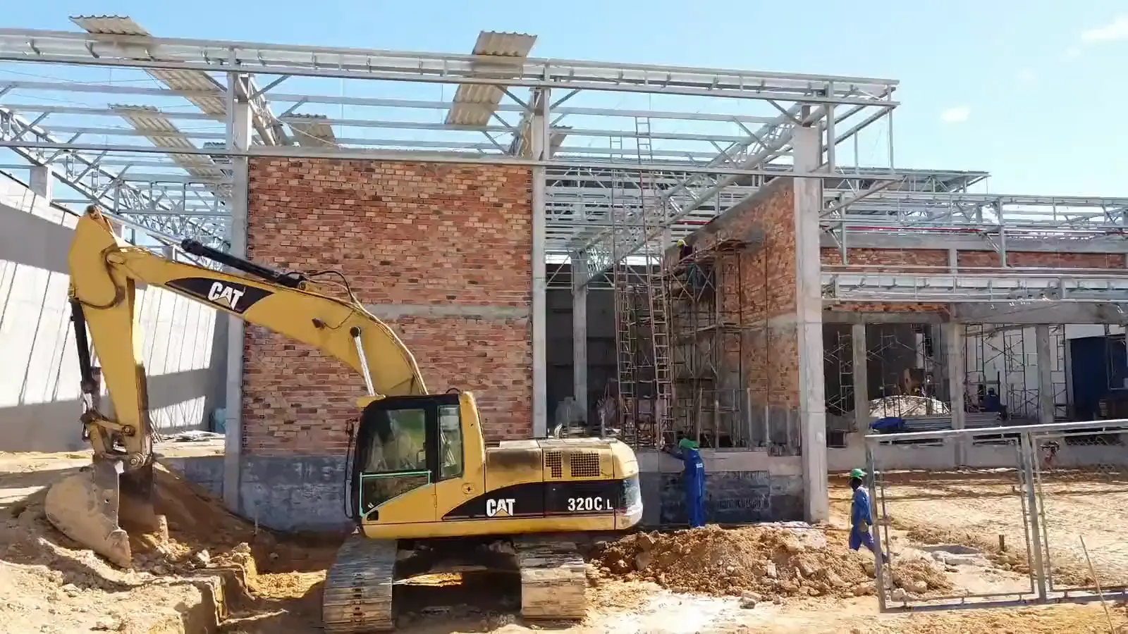 Ampliação de galpão industrial em execução, com escavadeira e estrutura metálica, em Manaus