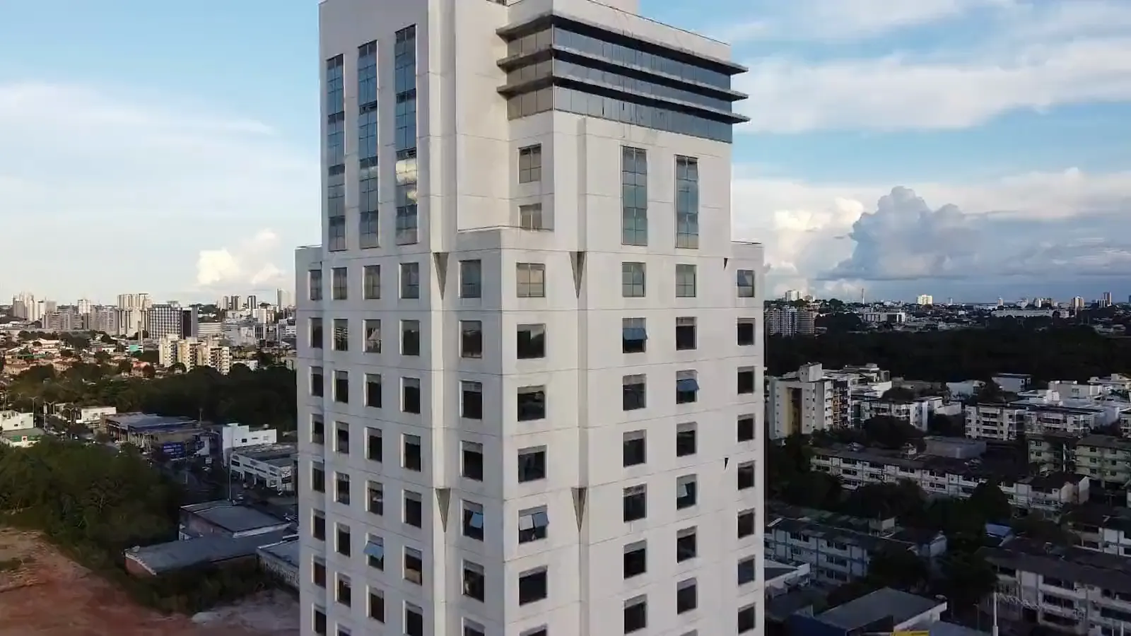 Torre de escritórios vista de drone, subindo pela fachada até o topo, sobre a cidade de Manaus